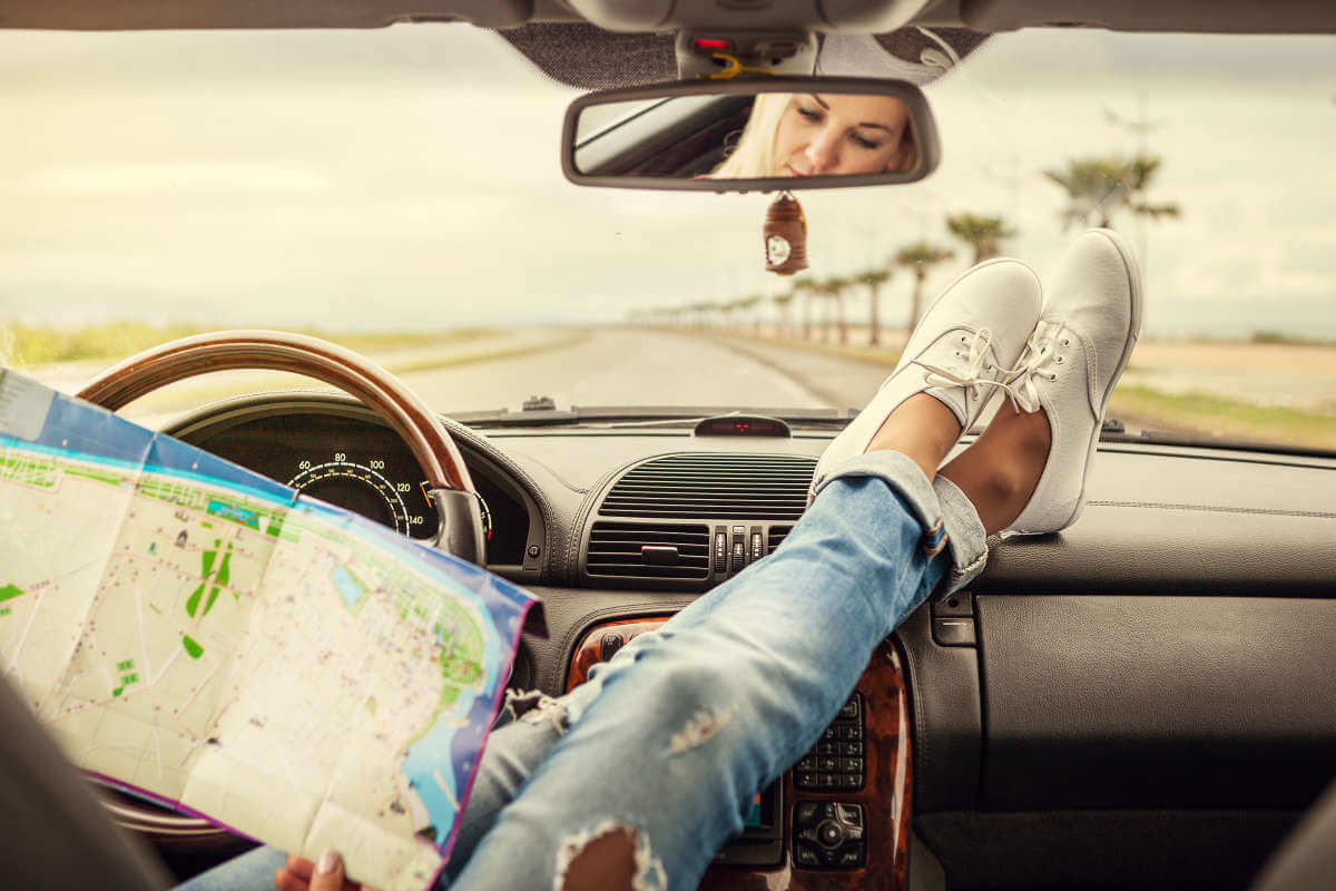 Girl on roadtrip looking at map in car